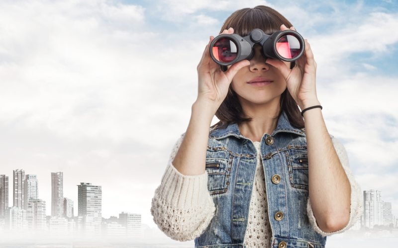 portrait of a pretty young woman looking through of the binoculars